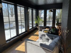 a sunny sunroom with wood floors and black painted walls