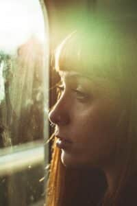 a woman looking wistfully outside through a window